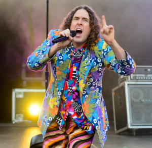 Weird Al Yankovic sings on a stage
