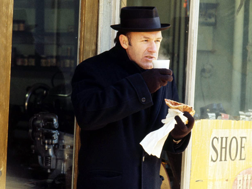 A New York police detective stands in the cold and eats a slice of pizza.