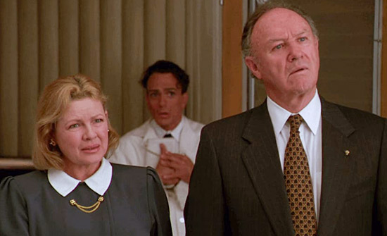 A US Senator and his wife look on in confusion while a nervous and shoeless butler stands behind them.
