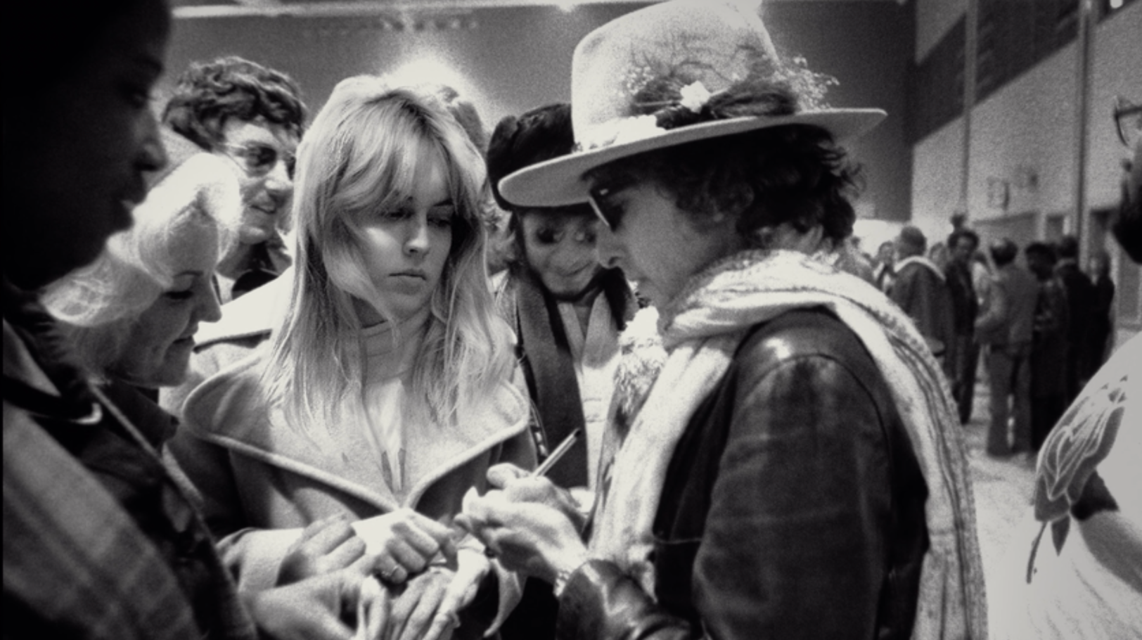 Bob Dylan wears a light hat and signs autographs for a young Sharon Stone