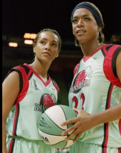 A men's basketball player, disguised as a woman, stands with a teammate
