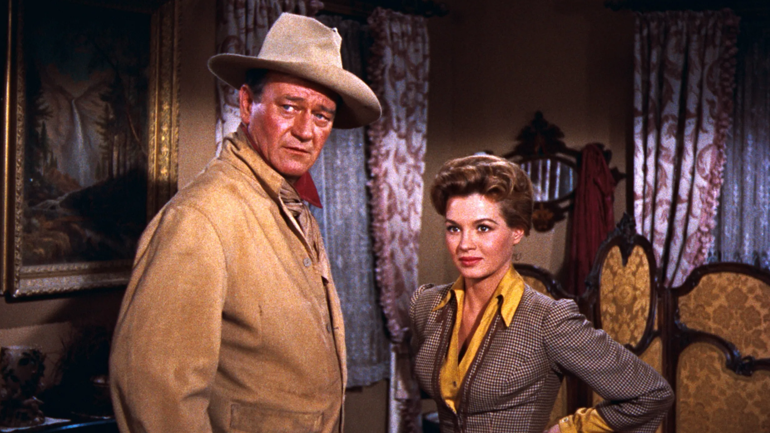 John T. Chance and Feathers stand in a hotel room and look offscreen